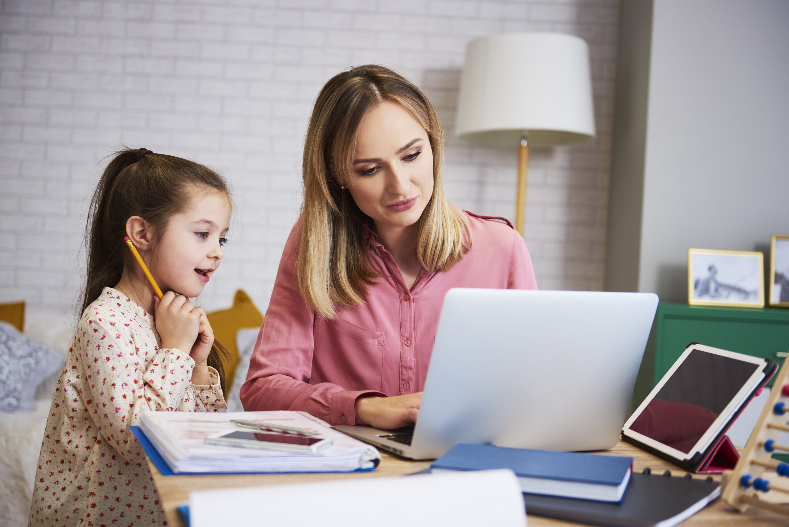 Young mother working from home with daughter Young mother working from home with daughter