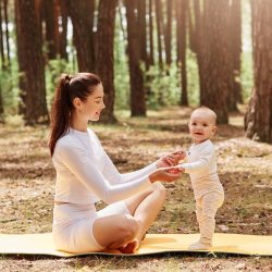 happy-smiling-female-white-trendy-sportswear-sitting-gym-mat-outdoor-holding-kids-palms